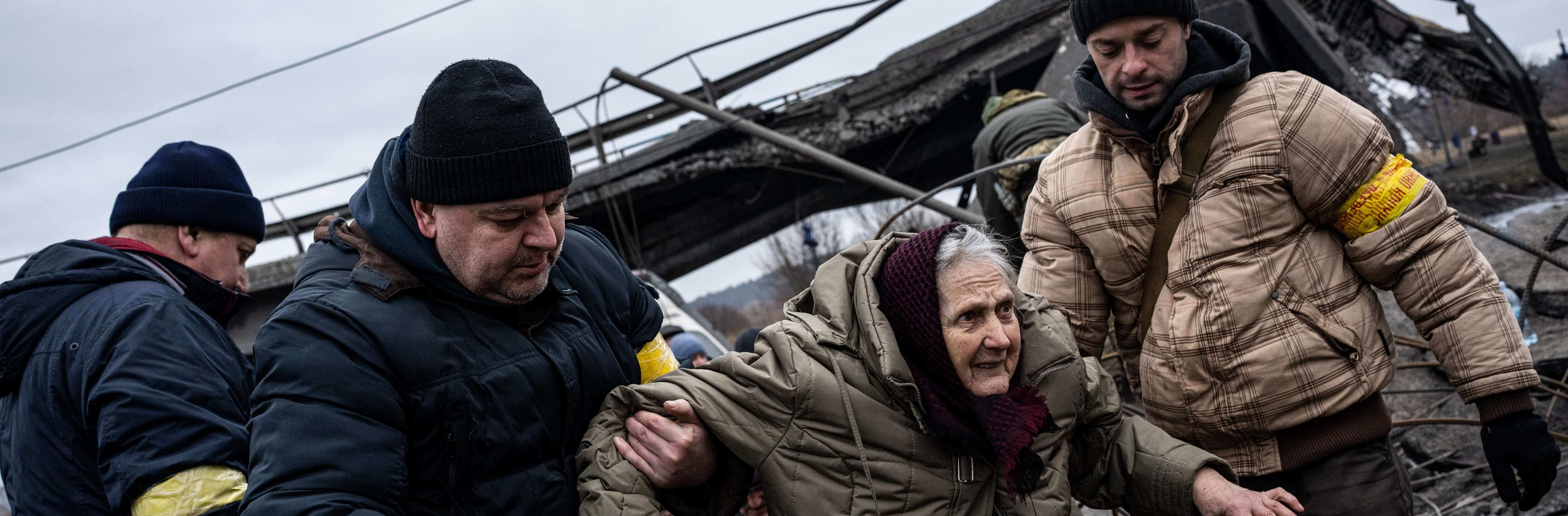 Menschen helfen einer älteren Frau bei der Flucht aus der Stadt Irpin in der Nähe von Kiew